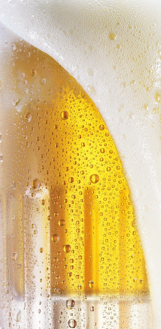 Beer foam flowing over the top of a glass (close-up)