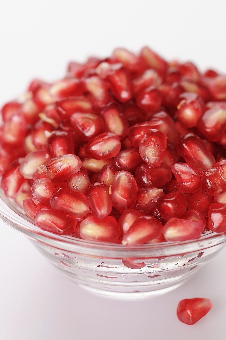 Pomegranate seeds in a glass bowl (close-up)