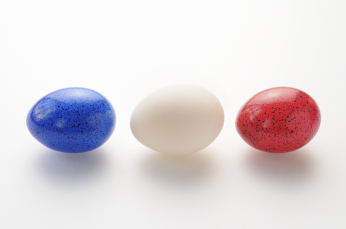 Ein weisses Ei zwischen zwei gefärbten Eiern