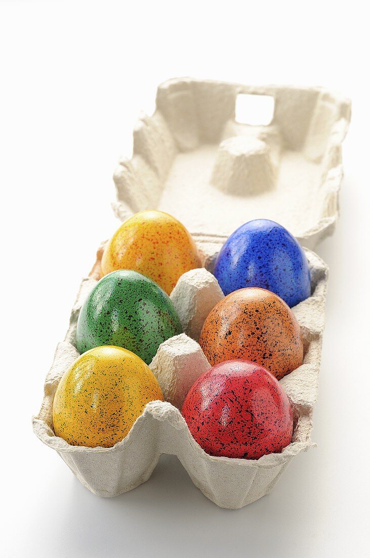 Sechs gefärbte Eier im Eierkarton