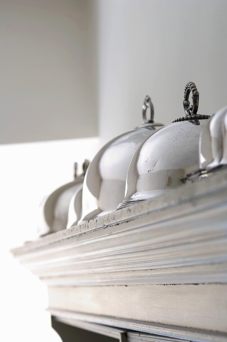 Silver cloches on top of a cupboard