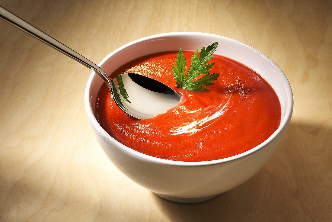 A bowl of tomato soup with a spoon