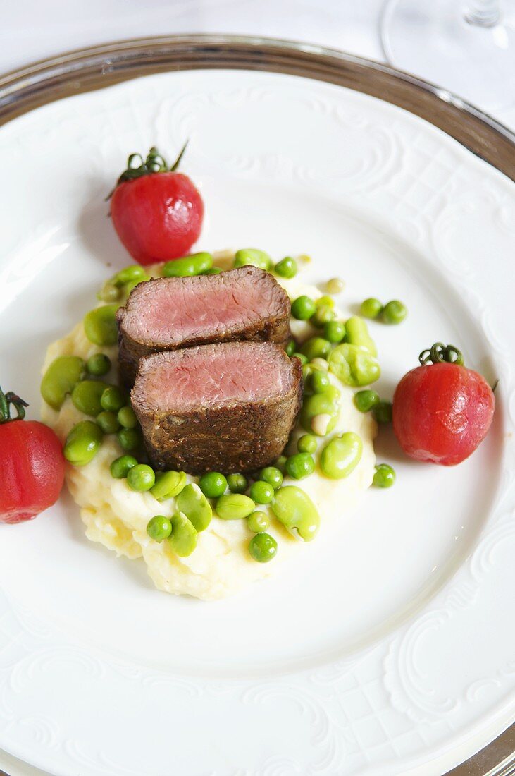 Saddle of lamb with beans and peas on a bed of mashed potatoes