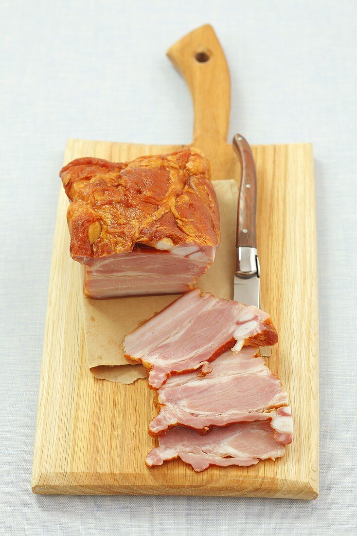 Smoked bacon and a knife on a wooden board