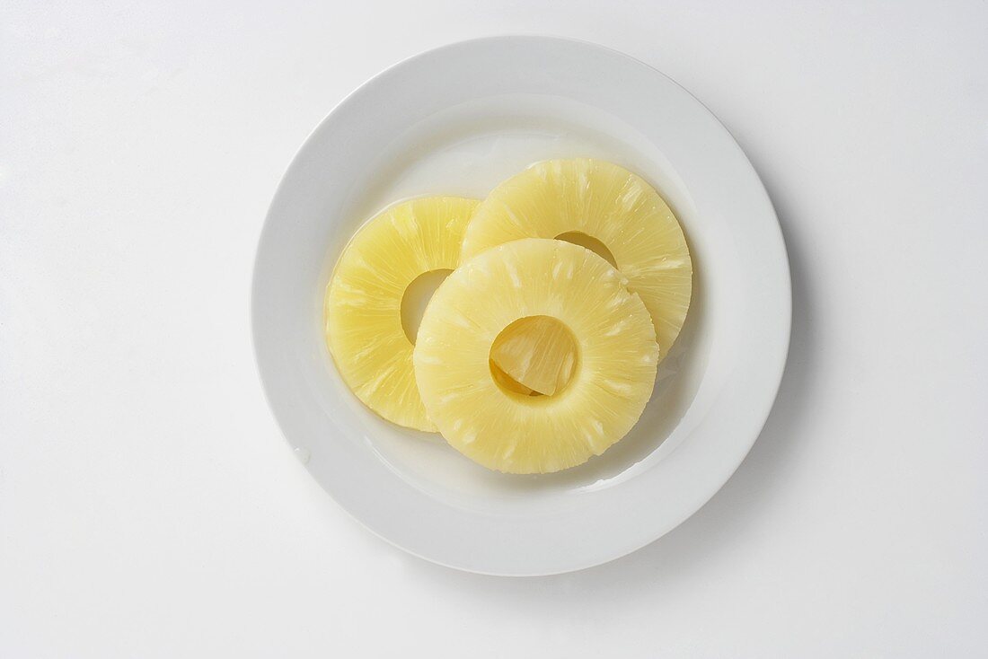 Three pineapple slices on a plate, seen from above