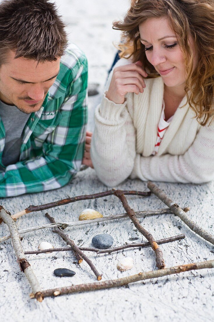 A couple play noughts and crosses on the beach