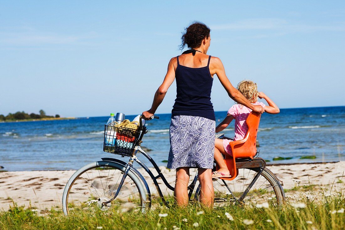 A mother and daughter with a bike on the beach