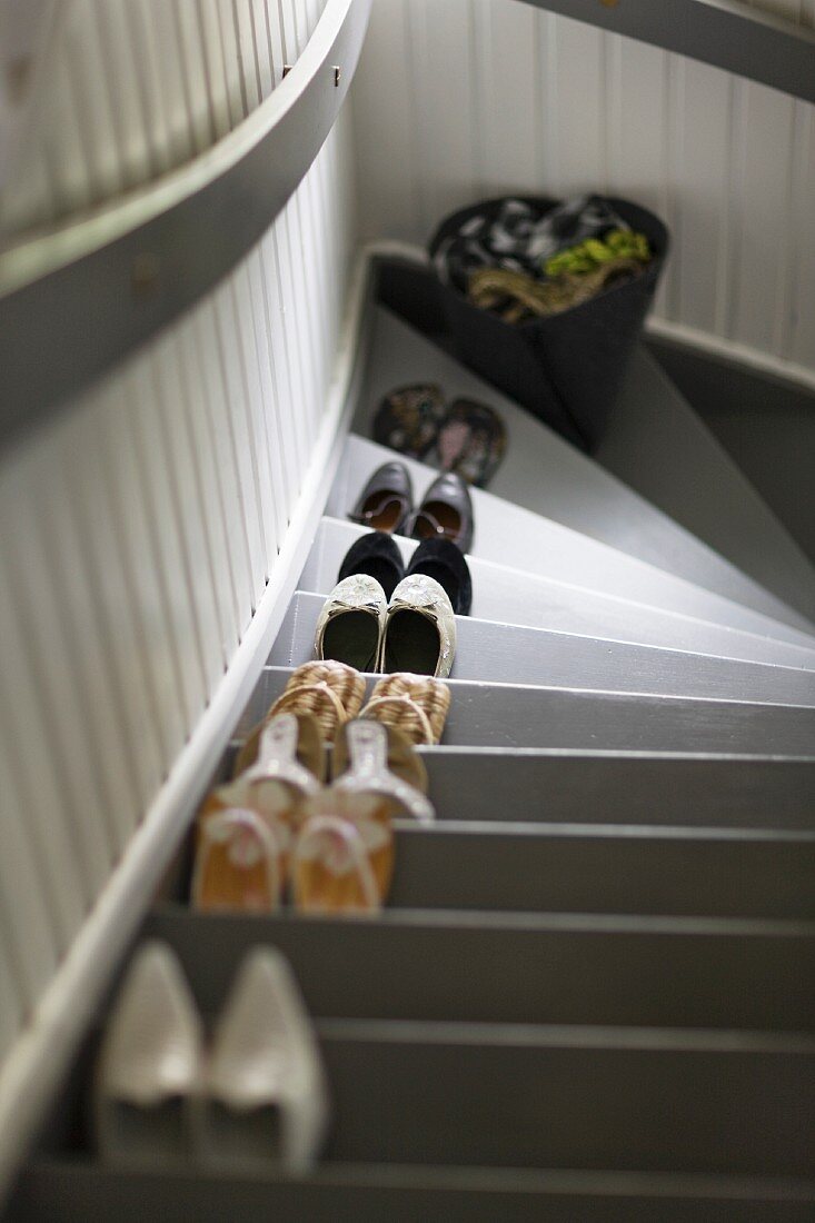 Various pairs of shoes, one on each step of a flight of stairs