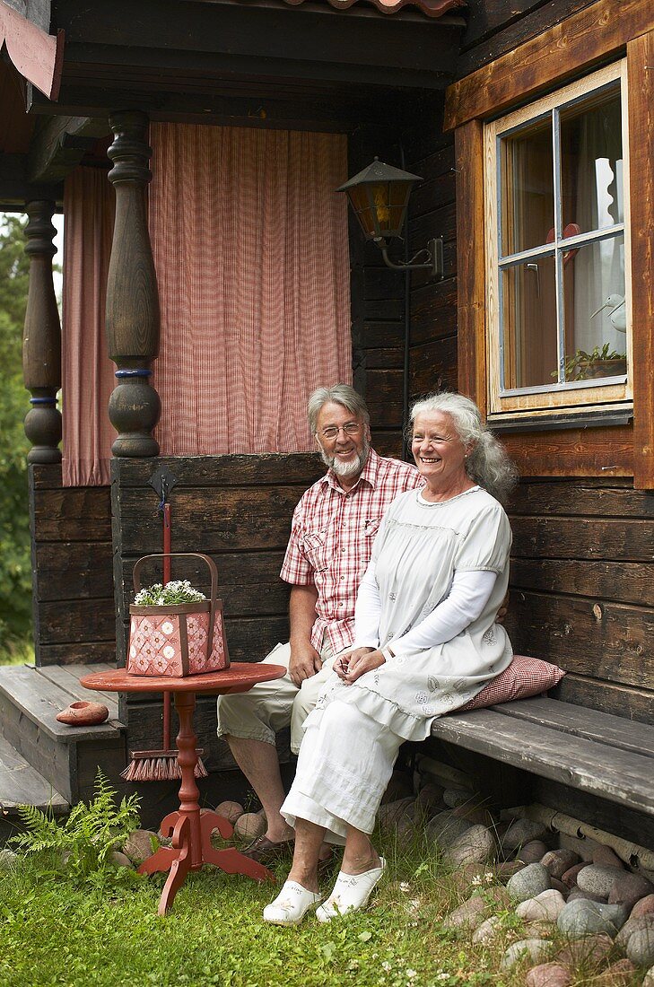 An old couple sitting outside a farm house