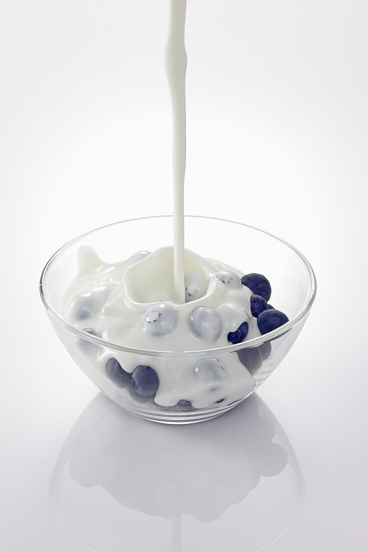 Yogurt being poured over blueberries