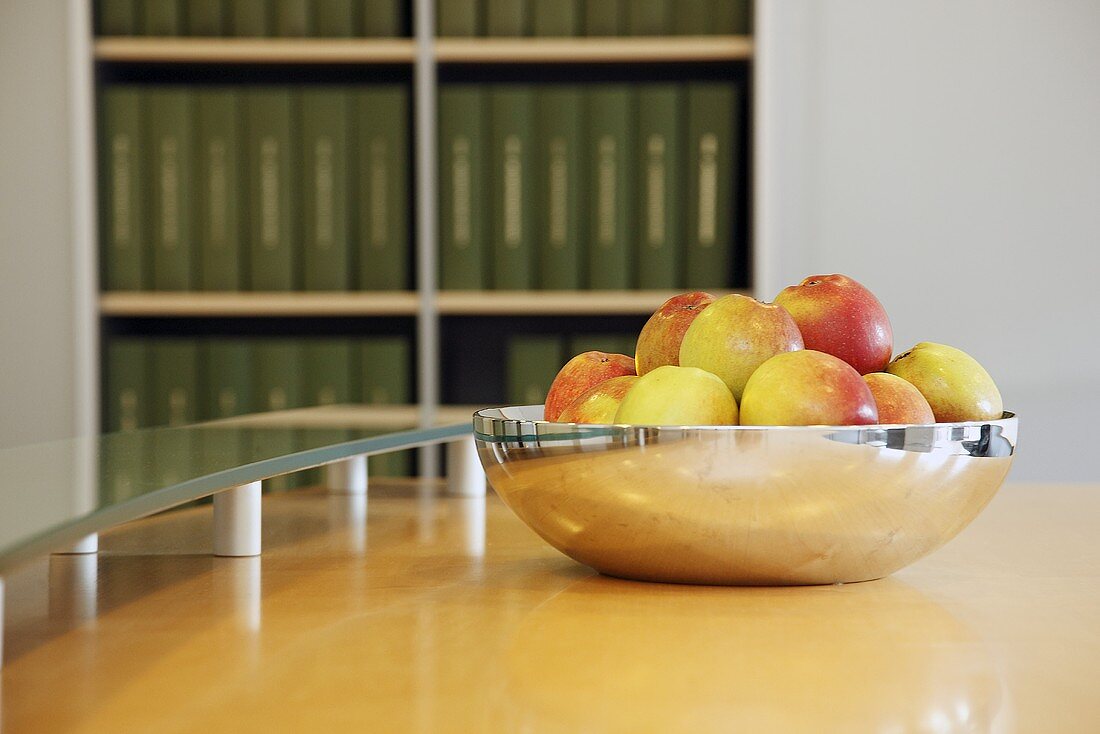 Fresh apples in a silver bowl on a table