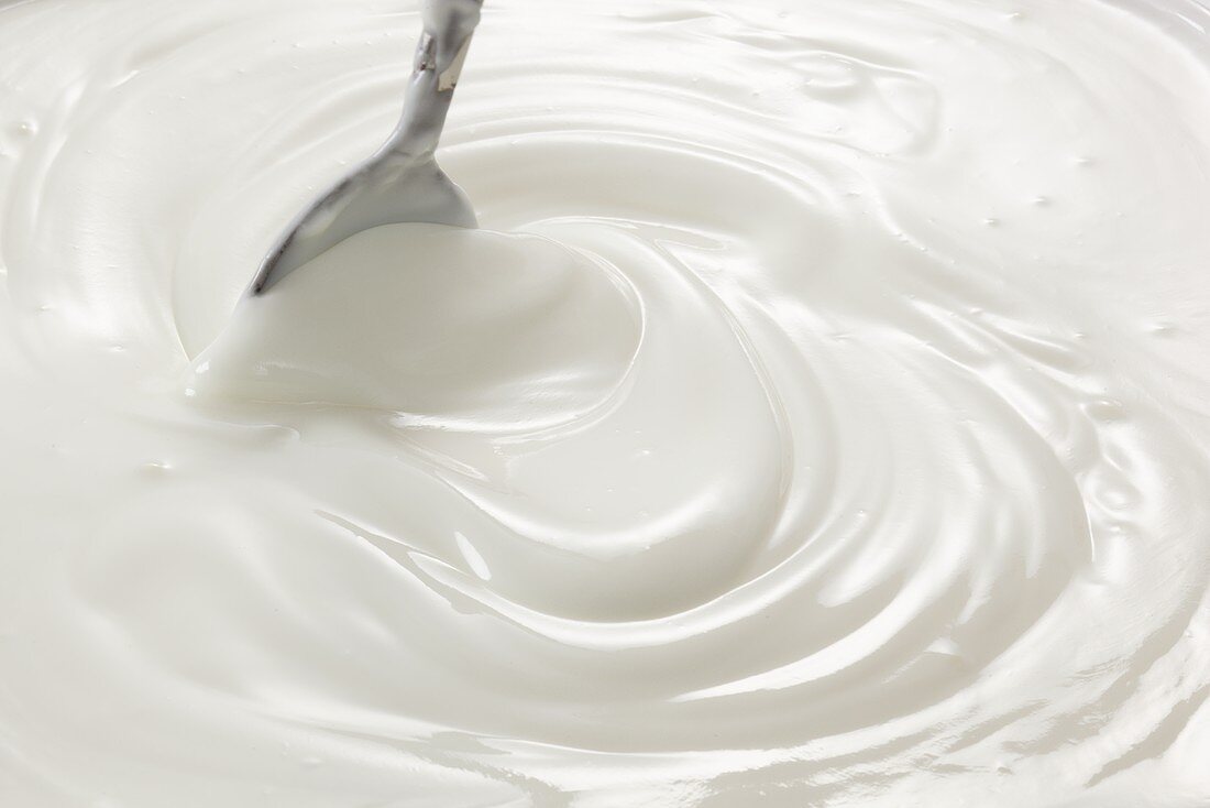 Natural yogurt being stirred with a spoon