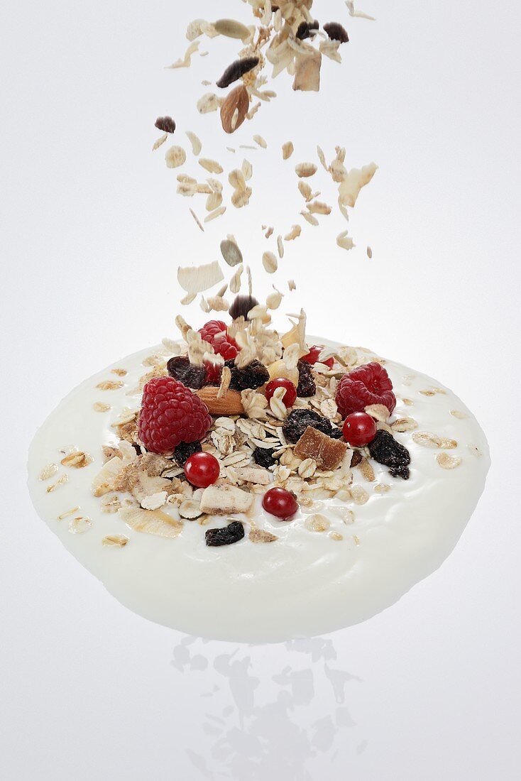 Fruit muesli falling into a dollop of yogurt