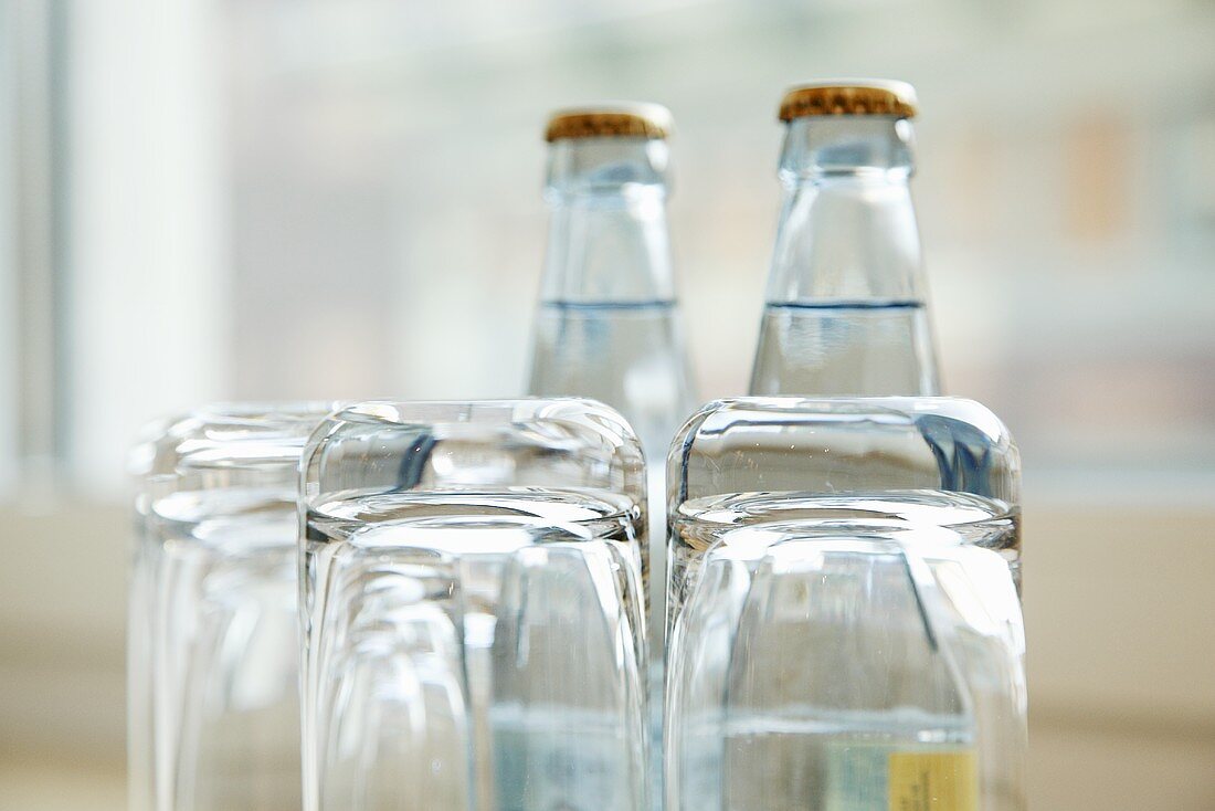 Umgedrehte Wassergläser vor Wasserflaschen