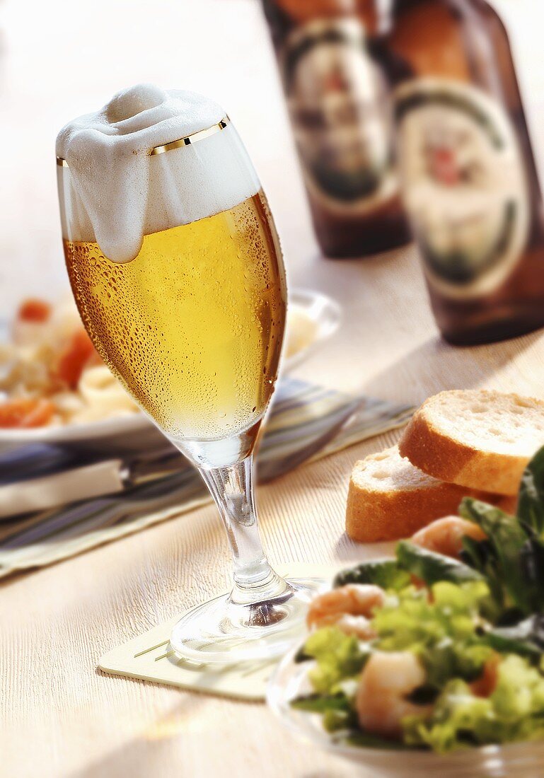 A glass of beer, salad and beer bottles