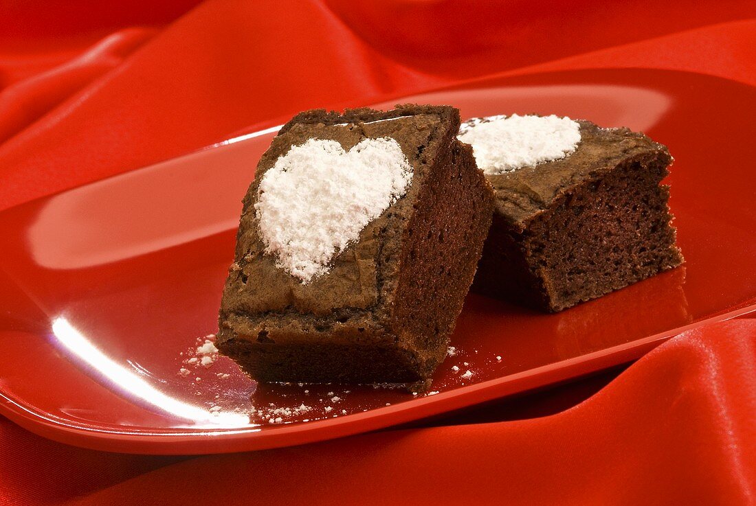 Brownies mit Puderzuckerherzen auf rotem Teller