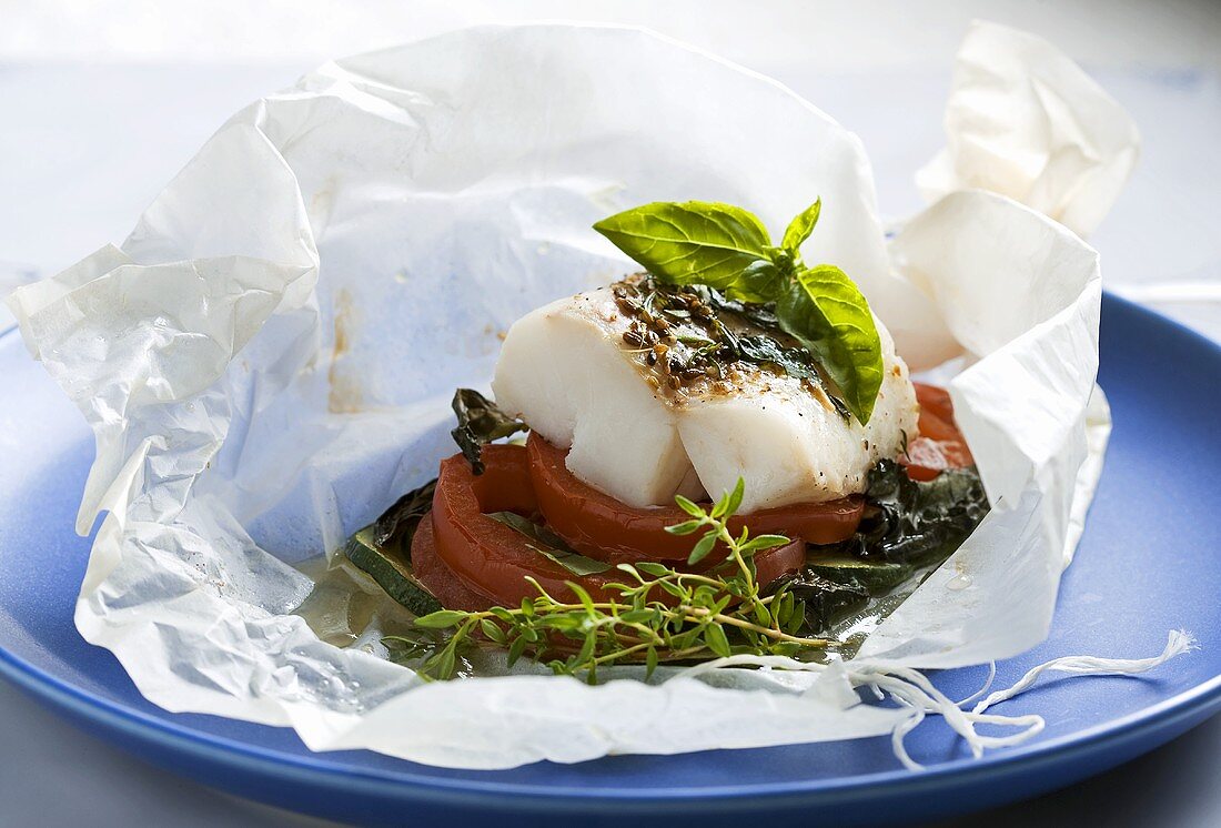 Fish fillet with tomatoes and courgette in baking paper