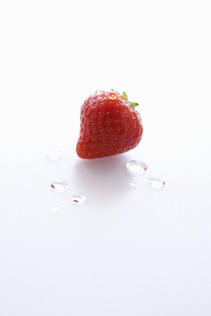 A Single Wet Strawberry on a White Background