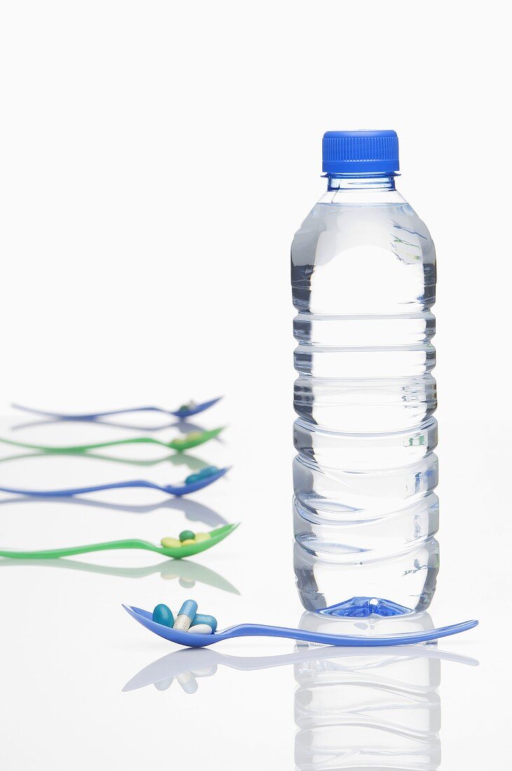 Mineralwasserflasche und Löffel mit Vitaminpillen