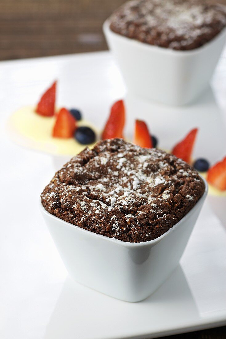 Chocolate souffle with icing sugar, berries and vanilla sauce
