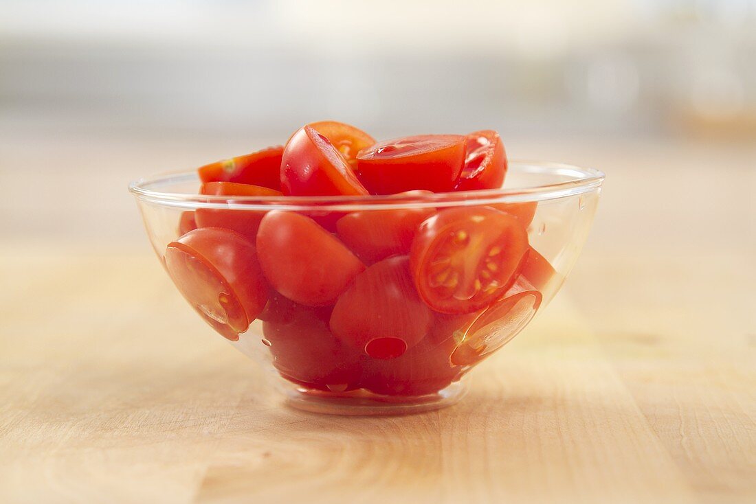 Halved tomatoes on a glass bowl