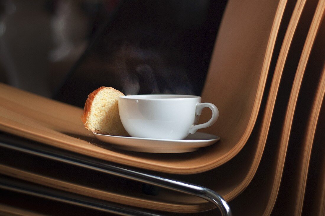 Kaffeetasse und Brioche auf Bürostuhl