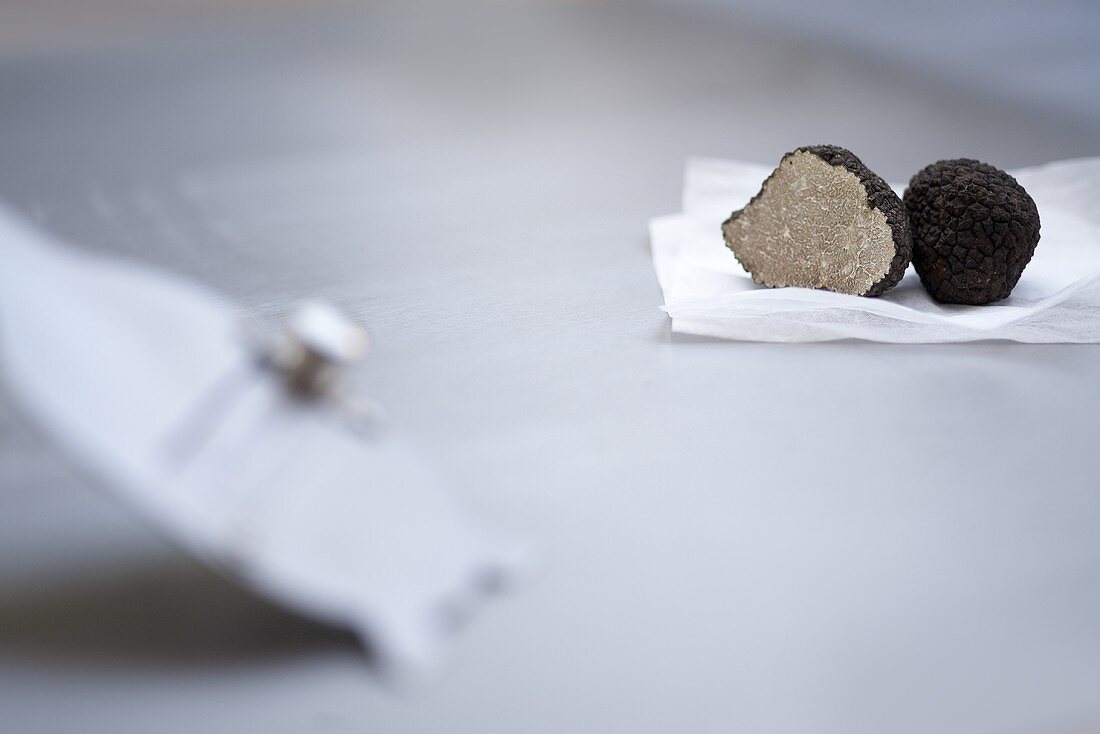 Black truffles, halved, on paper, on a truffle slice