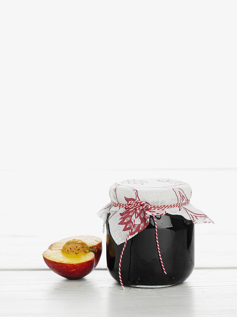 A jar of peach jam with half a peach next to it