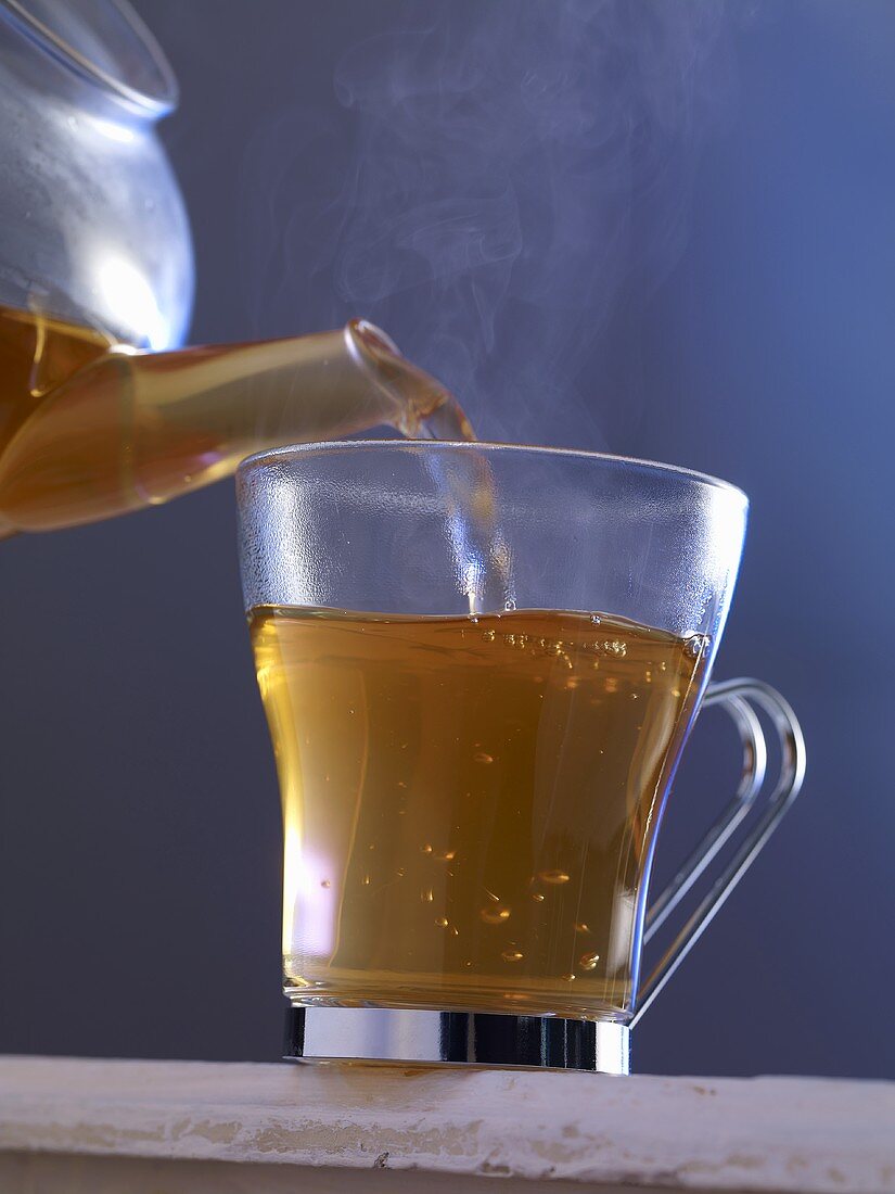 Hot tea being poured into a glass