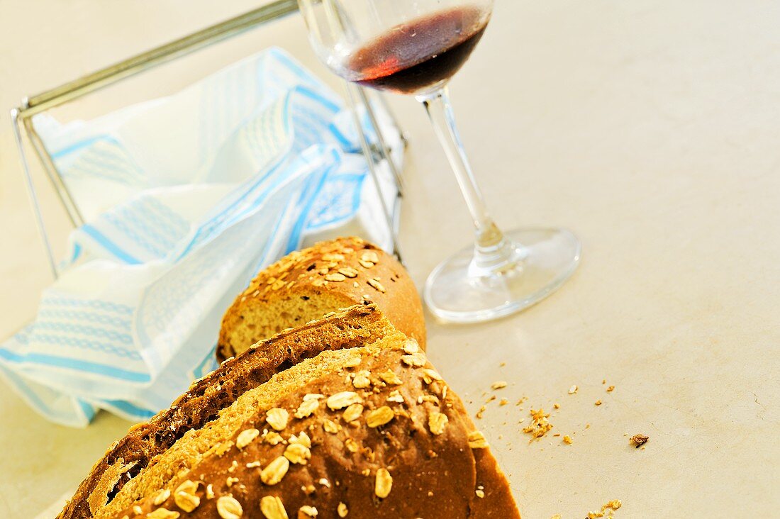 Angeschnittene Brote, dahinter Glas Rotwein & Servietten