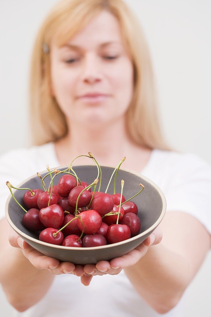 A woman holding a bowl of cherries