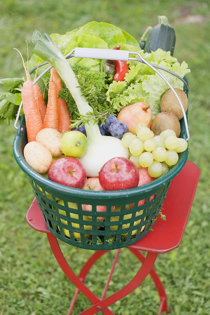 A basket of fresh fruit and vegetables on a garden table