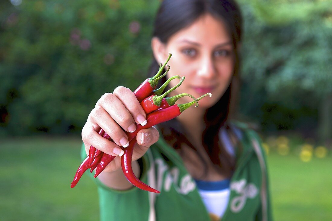 Frau hält frische rote Chilischoten
