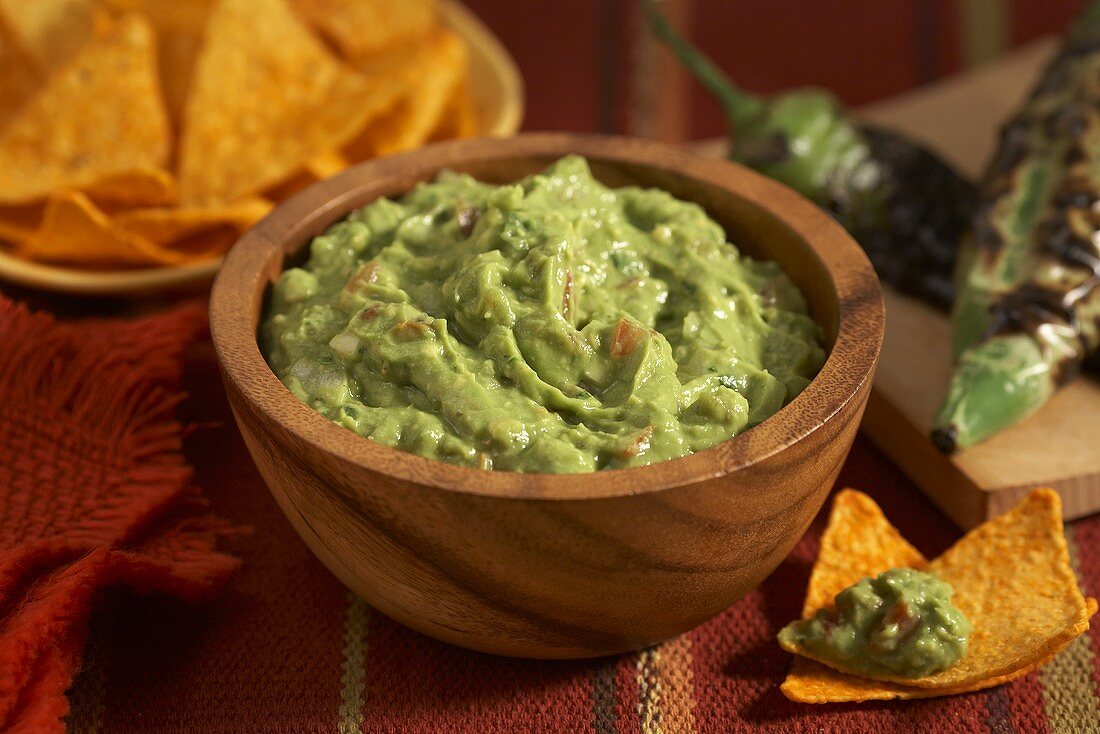 Guacamole in a Wooden Bowl; Tortilla Chips; Charred Jalapeno Peppers