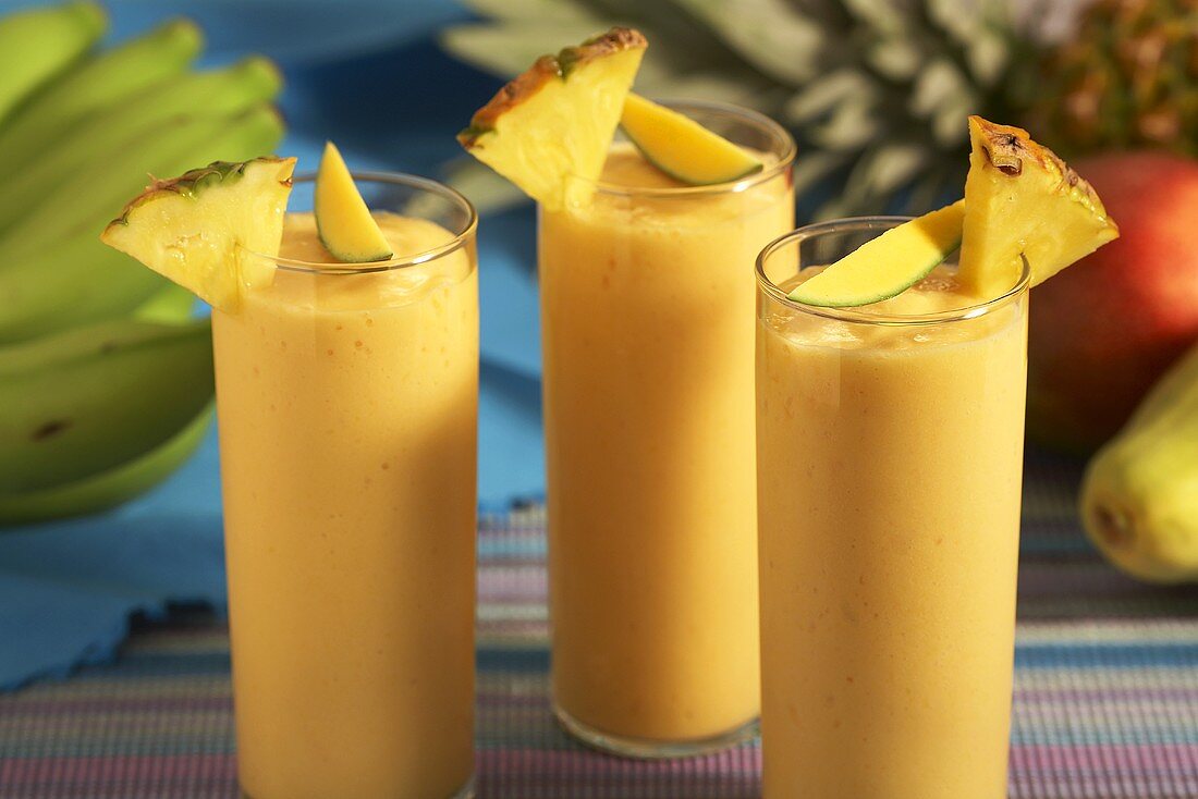 Papaya, Banana, Pineapple Smoothies in Glasses with Fresh Fruit Garnish