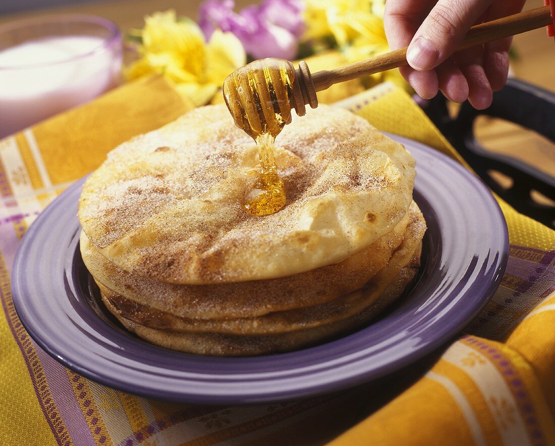 Hand Drizzling Honey Over Sopapillas (Mexican Fried Pastry)