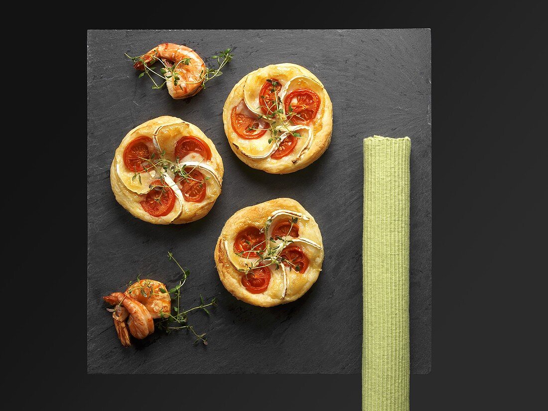 Puff pastry tartlets with goat's cheese and tomatoes on a slate plate