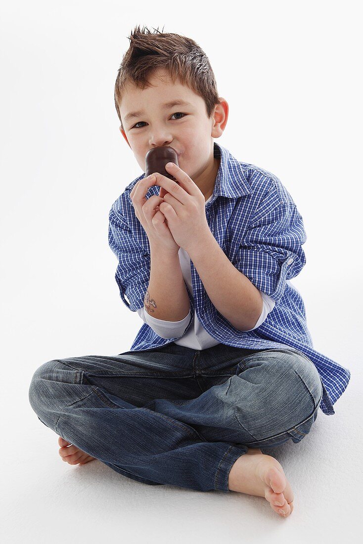 A little boy eating a chocolate marshmallow