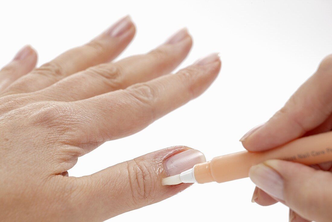 A woman applying a care product to her nail bed