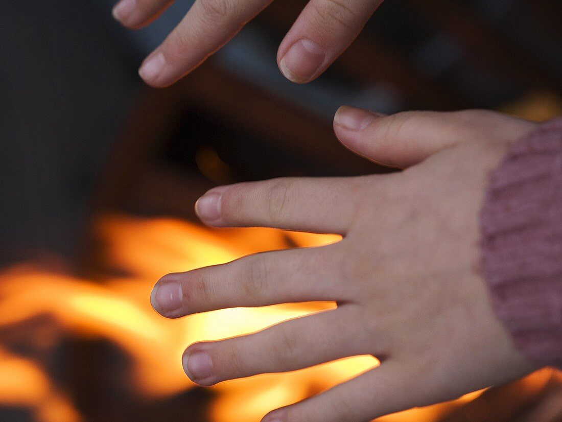 Hands being warmed over a fire