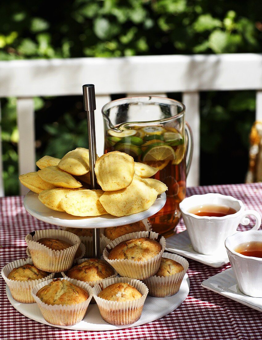 Etagere mit Madeleines und Muffins, dazu Eistee