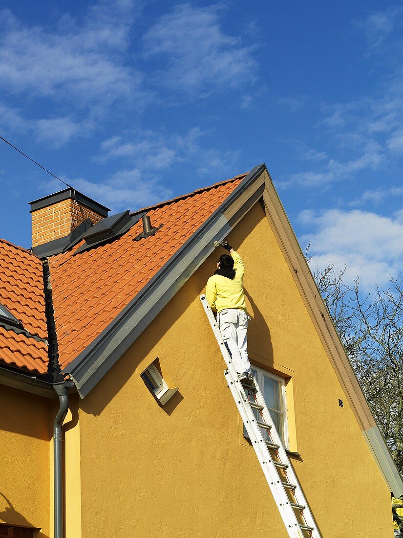 Mann beim streichen eines Dachgiebels