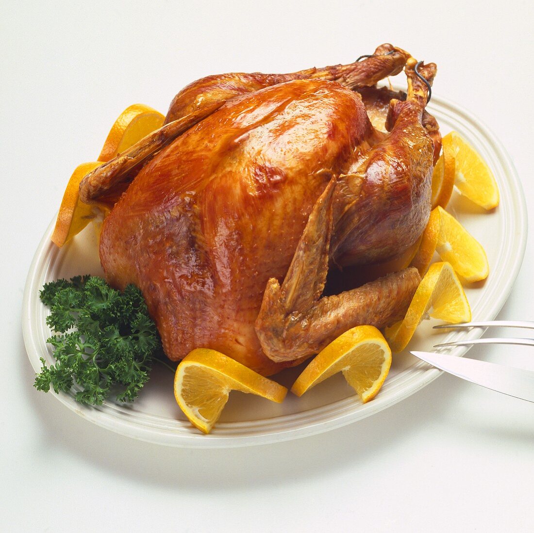 Whole Roast Turkey with Orange Slice Garnishes on a Platter; Carving Set