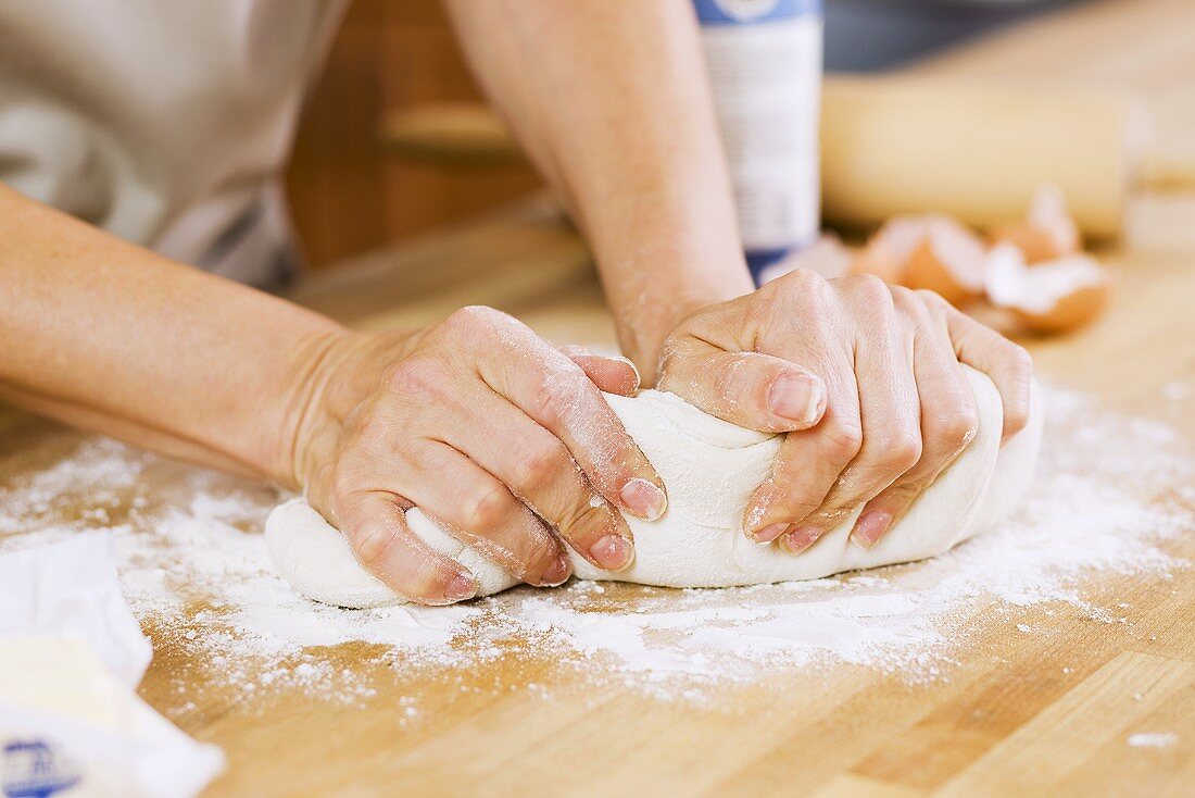 Woman Kneading Dough on Floured Counter in Kitchen