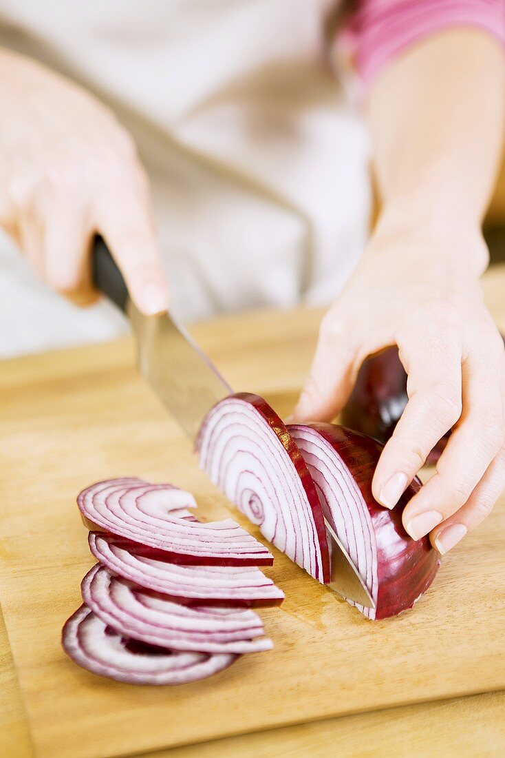 Frau schneidet rote Zwiebel