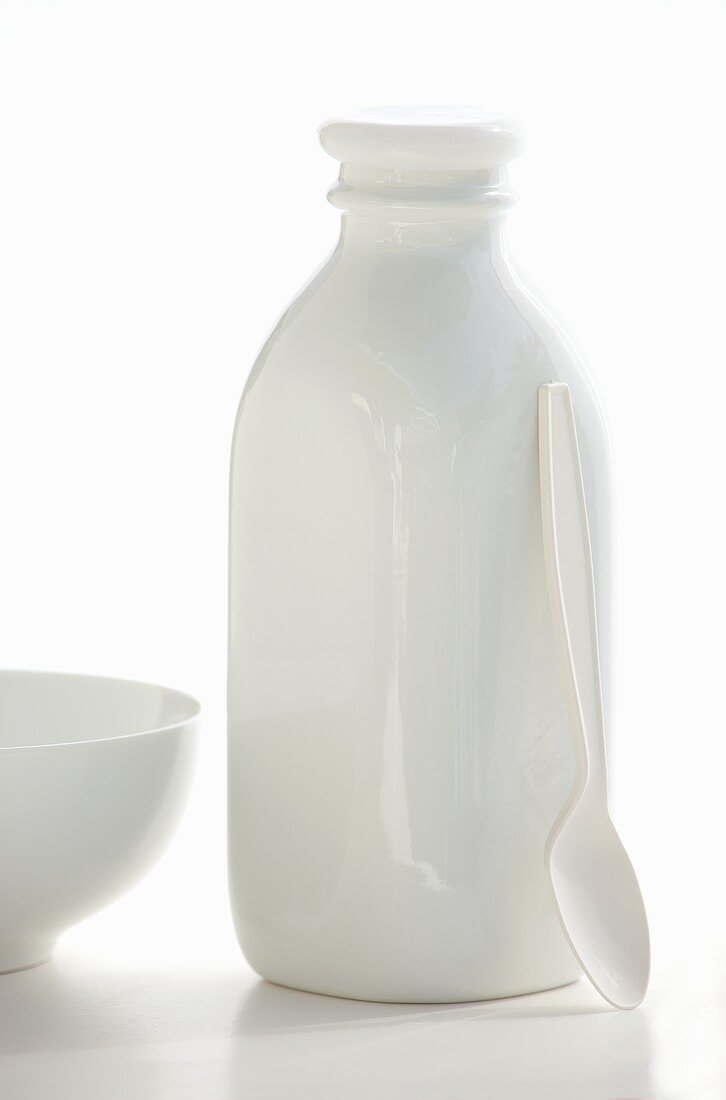 Milchflasche, Löffel und Schüssel in Weiß