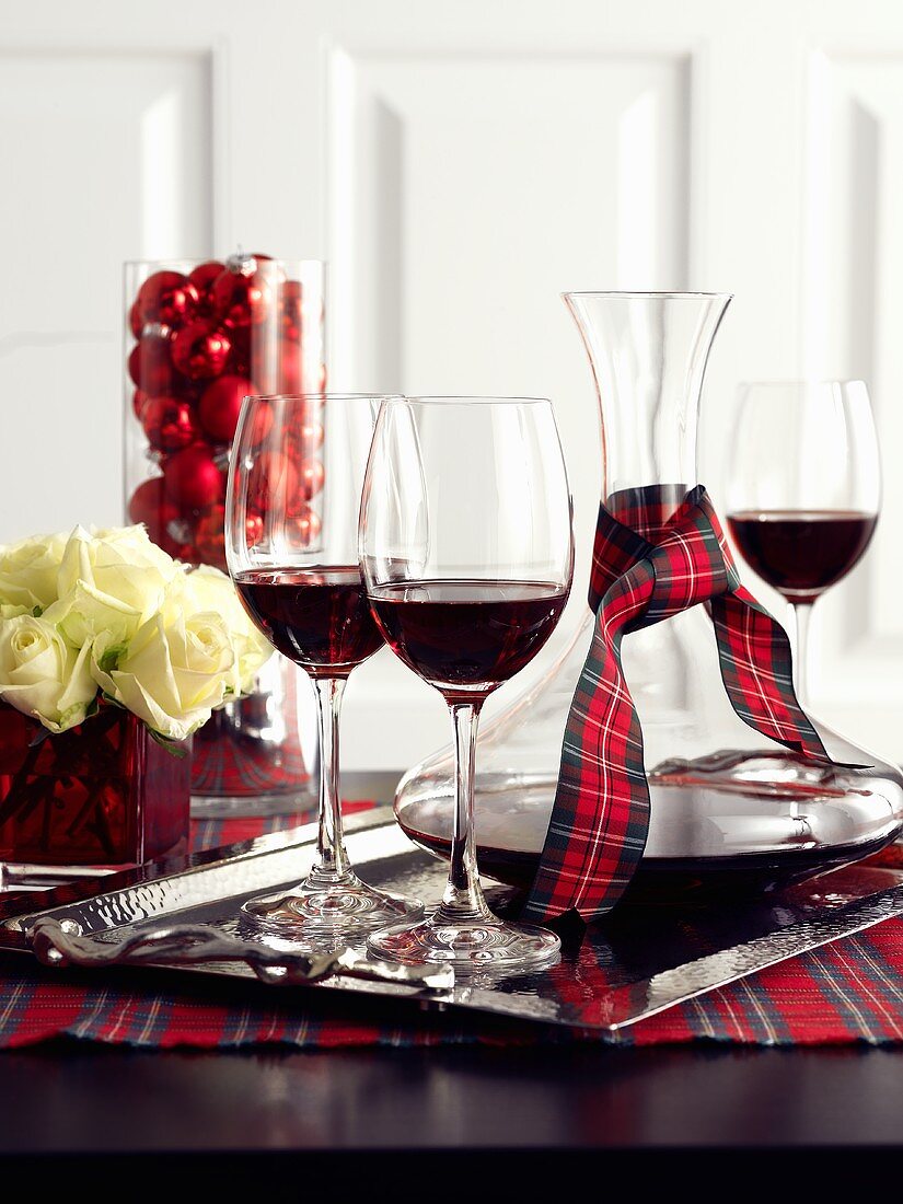 Red wine in glasses and carafe on a table decorated for Christmas