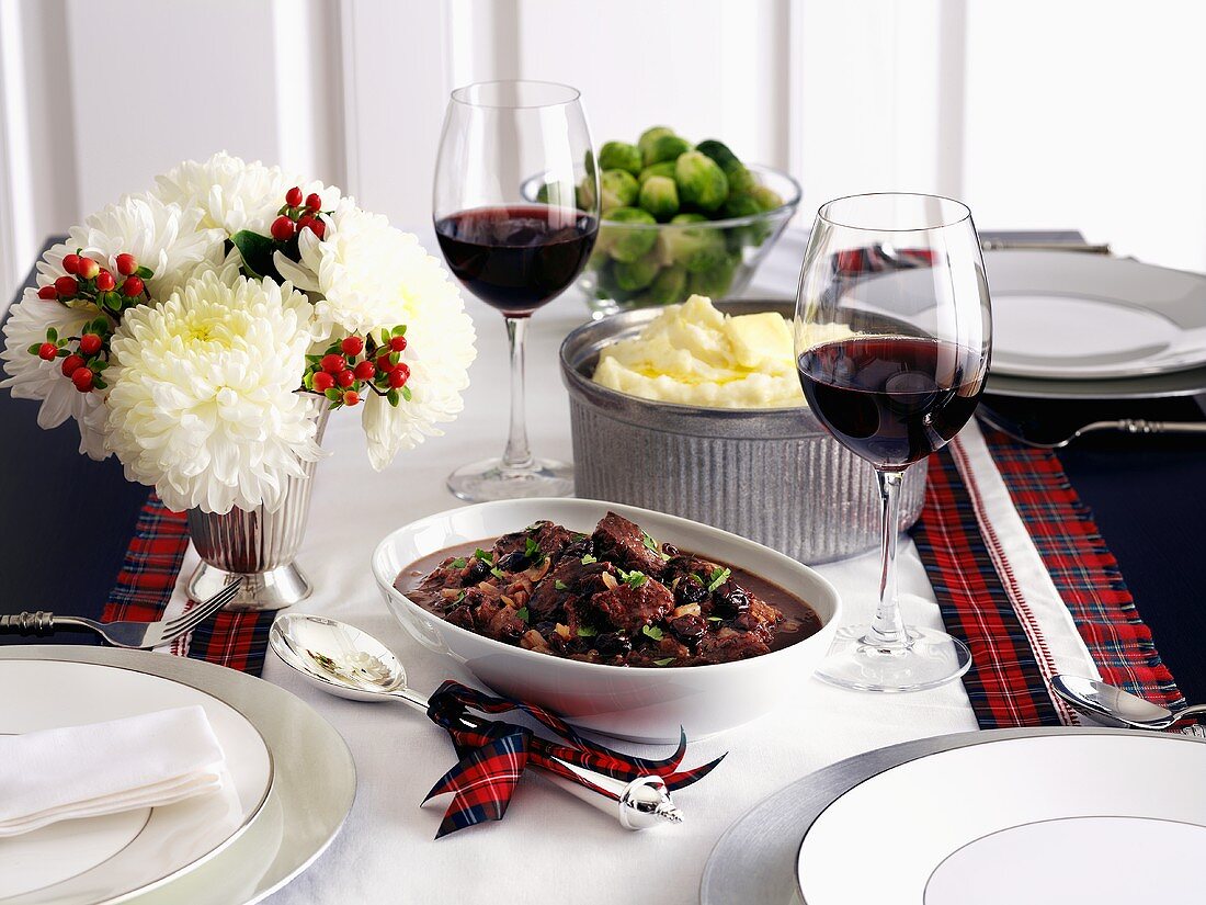 Rehrücken mit Kirschen, Kartoffelpüree und Rosenkohl auf einem weihnachtlich gedeckten Tisch
