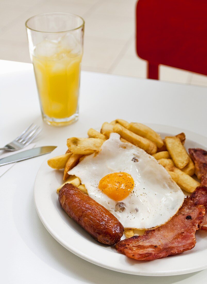 Englisches Frühstück mit Spiegelei, Bratwurst, Speck und Pommes