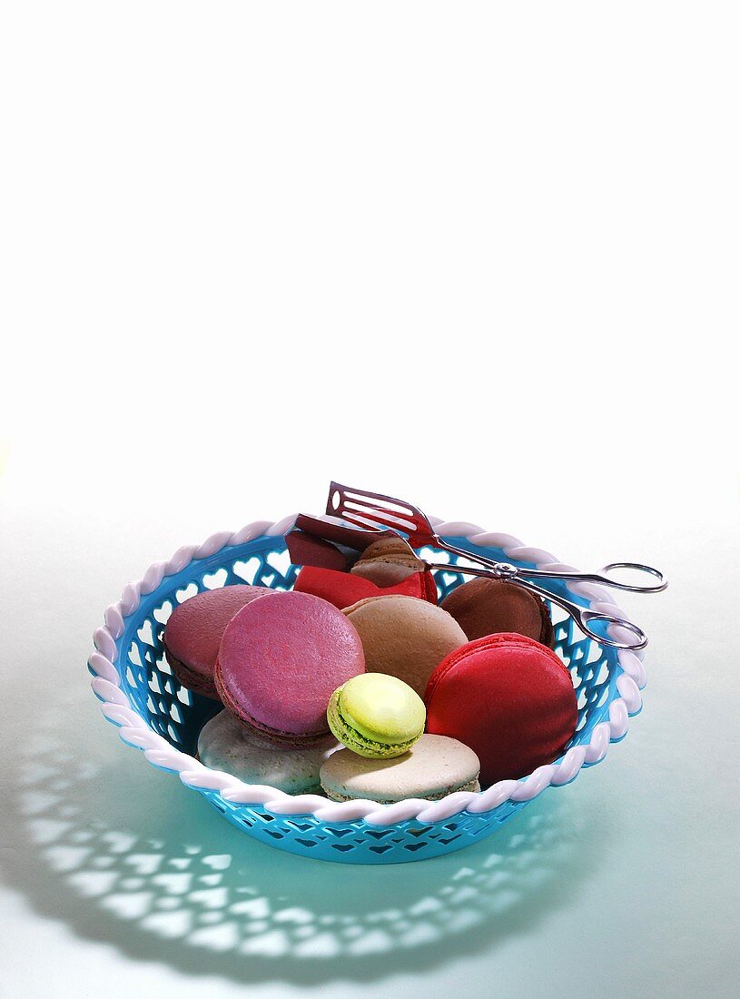 Different types of macaroons in a basket with tongs